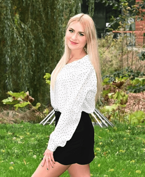 A woman standing in the grass wearing a skirt.