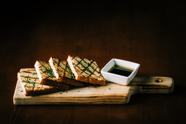 A wooden cutting board with some bread and sauce on it