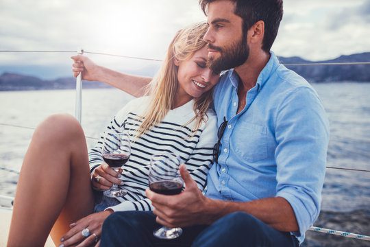 A man and woman sitting next to each other holding wine glasses.