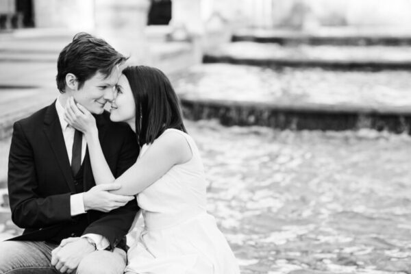 A man and woman hugging each other in front of water.