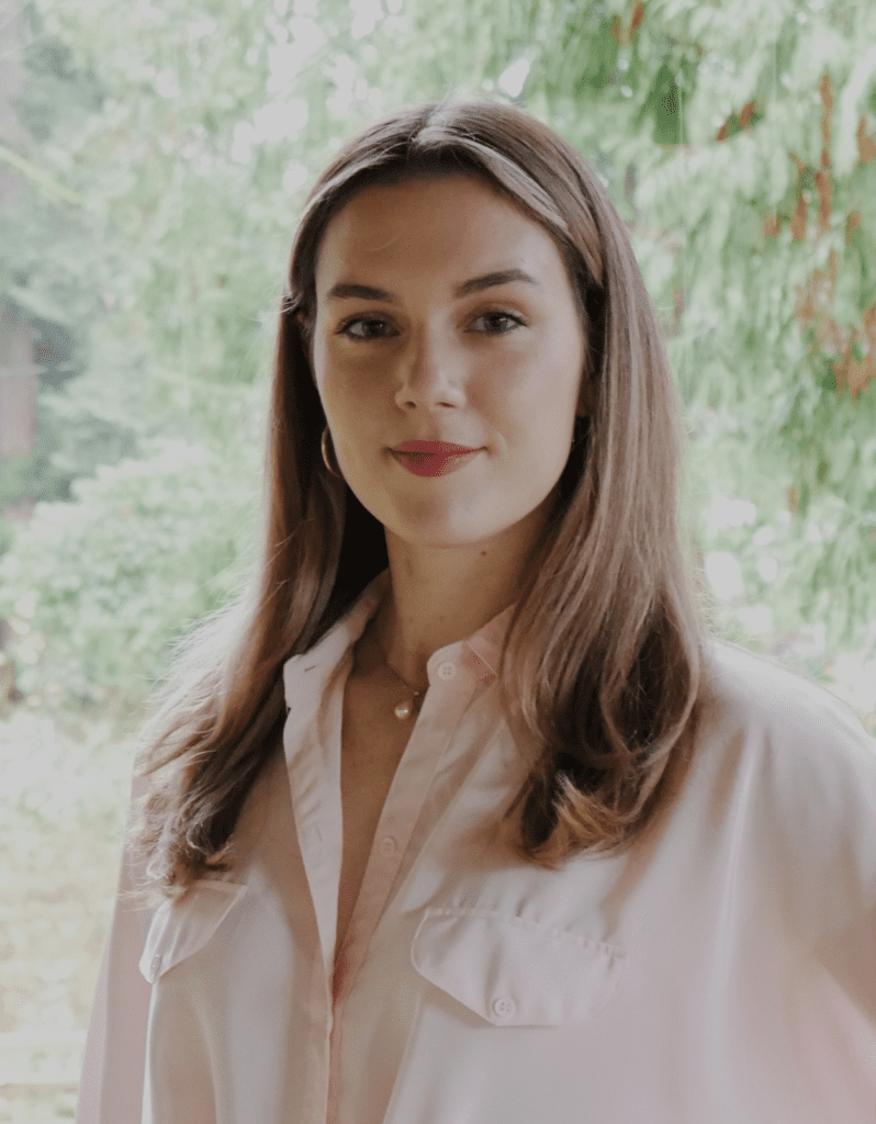 A woman in pink shirt standing next to trees.