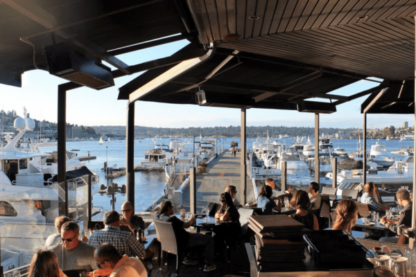 A group of people sitting at tables near water.