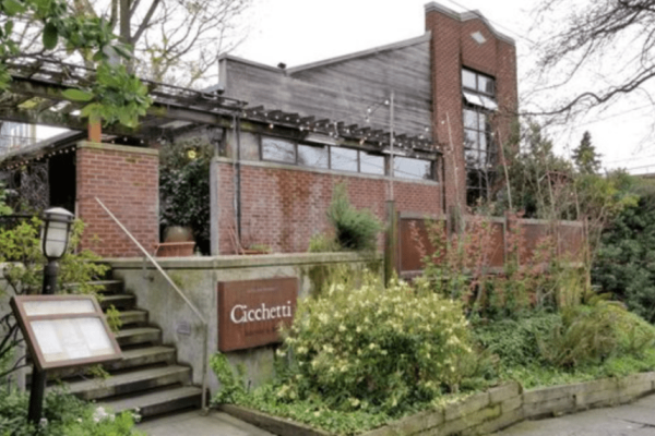 A building with plants and flowers in front of it.