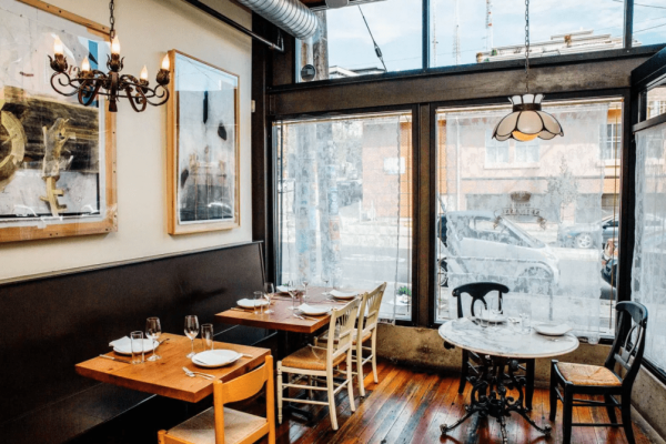 A restaurant with tables and chairs in front of the windows.