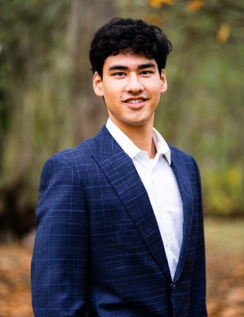 A man in a suit and tie standing outside.